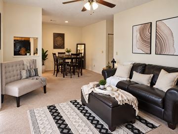 Fort Wayne townhouse for rent - A living room with a grey sofa, a black leather couch, a dining table with chairs, and a rug on the floor.