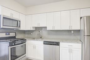 Jeffersonville apartment for rent - a kitchen with white cabinets and stainless steel appliances