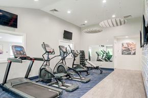 Jeffersonville apartment for rent - a gym with cardio equipment and a tv on the wall