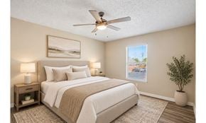 Irving townhouse for rent - A bedroom with a bed, two lamps, a ceiling fan, and a plant.