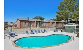 Irving townhouse for rent - A pool surrounded by chairs and a building in the background.