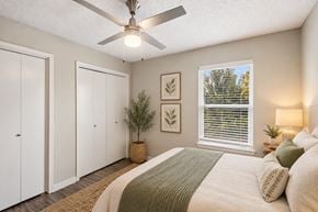 Oklahoma City apartment for rent - A bedroom with a bed, a ceiling fan, and a window with blinds.