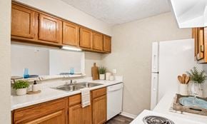 Oklahoma City apartment for rent - A kitchen with wooden cabinets and white appliances.
