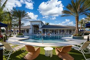 Lake Worth Corridor apartment for rent - A poolside area with chairs and the clubhouse in the background.