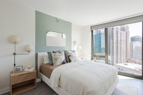 Chicago apartment for rent - A bedroom with a large bed and a view of the city.