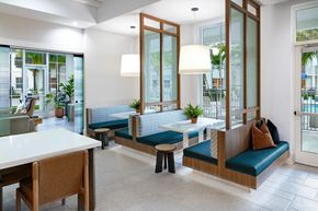 Lake Worth Corridor apartment for rent - A modern resident lounge with sitting booths with white table and blue cushions.