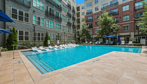 Atlanta apartment for rent - A swimming pool surrounded by lounge chairs and umbrellas in front of a building.