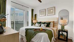 Atlanta apartment for rent - A bedroom with a large bed and a view of a cityscape through the window.