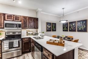Austin apartment for rent - 3 Bedroom Apartments in North Austin, TX - Sycamore Springs - Modern Kitchen with Quartz Counters, Wooden Cabinetry, Stainless Steel Appliances, a Dining Area, and Faux Plank Flooring 