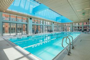 Salt Lake City apartment for rent - A large indoor swimming pool with a blue tiled floor and a glass ceiling.