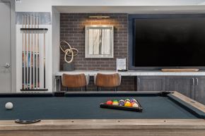 Mesa apartment for rent - a pool table and a tv in a room with a brick wall