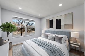 Ogden apartment for rent - A bedroom with a large bed and a window overlooking a tree-lined street.