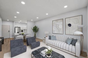 Ogden apartment for rent - A living room with a white couch, grey chairs, and a coffee table with a plant on it.
