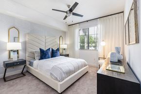 Boca Raton apartment for rent - A bedroom with a large bed, a ceiling fan, and a window with curtains.