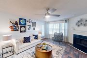 Birmingham apartment for rent - A living room with a white couch, a coffee table, a fireplace, and a ceiling fan at Inverness Cliffs, Alabama, 35242