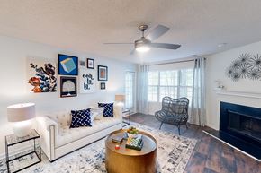 Birmingham apartment for rent - A living room with a white couch, a coffee table, a fireplace, and a ceiling fan at Inverness Cliffs, Alabama, 35242