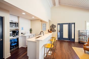 A kitchen with white cabinets and a white island with yellow chairs