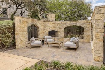 A patio with a stone wall and a fireplace