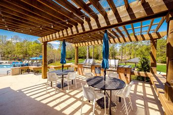 A covered patio with tables and chairs and a pool