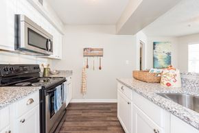 Birmingham apartment for rent - A kitchen with a black stove top oven and white cabinets. at WildForest Apartments, Birmingham, AL