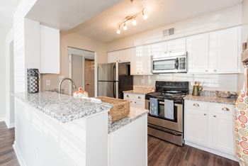 A kitchen with white cabinets and a granite countertop.