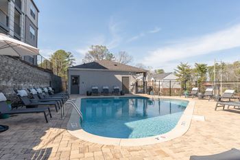 A swimming pool with lounge chairs and a building in the background