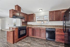 Cheyenne apartment for rent - A kitchen with wooden cabinets and black appliances at Country Lane, Cheyenne, Wyoming