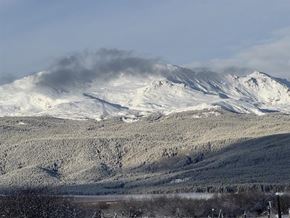 Leadville apartment for rent - A mountain range covered in snow with a cloud of smoke rising from the peak.