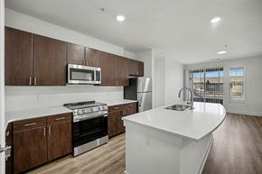 Wheat Ridge apartment for rent - A modern kitchen with dark wood cabinets and white countertops.
