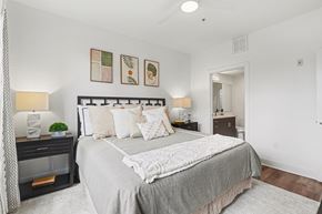 Wheat Ridge apartment for rent - A bedroom with a large bed and a nightstand with a lamp.