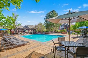 Littleton apartment for rent - A pool surrounded by chairs and umbrellas.