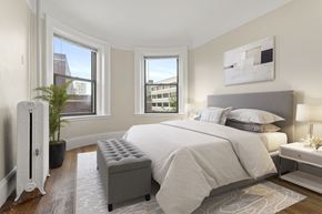 Cambridge apartment for rent - A bedroom with a large bed and a window overlooking a cityscape.