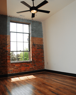 Suffolk apartment for rent - A room with a ceiling fan and a window with a brick wall.