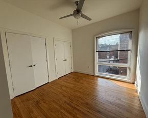 Richmond apartment for rent - A room with a ceiling fan and a window showing a view of a building outside.