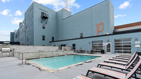 Norfolk apartment for rent - a swimming pool in front of a blue building with beach chairs
