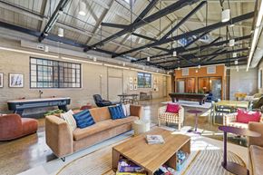 Martinsburg apartment for rent - A large, open-plan living area with a variety of seating options and a high ceiling with exposed beams.