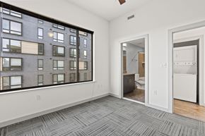 Richmond apartment for rent - A room with a grey carpet and a large window overlooking a building.