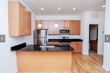 Portsmouth apartment for rent - A kitchen with wooden cabinets and black countertops.