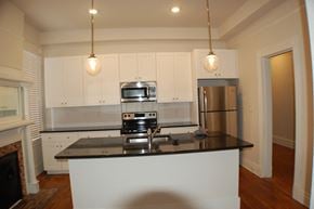 Richmond apartment for rent - A kitchen with white cabinets and a black countertop.