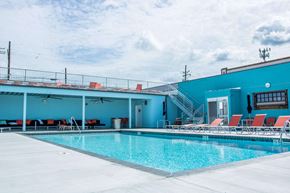 Norfolk apartment for rent - A large swimming pool with red lounge chairs and a blue building in the background.