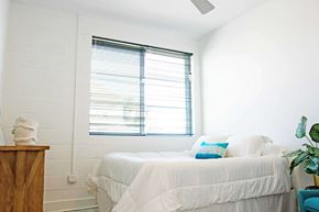 Norfolk apartment for rent - A white bedroom with a bed, pillows, a nightstand, and a plant.