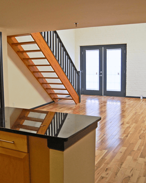 Richmond apartment for rent - A wooden staircase with a black railing leads to a white door.