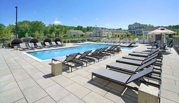 A pool with sun loungers and a building in the background.