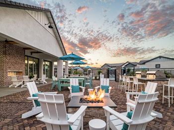 A patio with white chairs and a fire pit.
