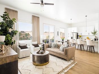 A modern living room with a large sectional sofa, a coffee table, and a dining area in the background.