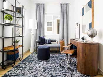 A living room with a couch and a desk and a rug