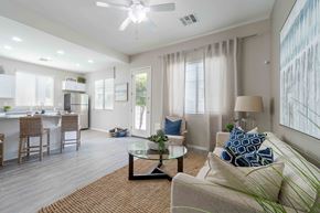 Tolleson apartment for rent - A well-lit living room with a couch, chairs, and a dining table. at Vistoria At Country Place Apartments, Tolleson, Arizona