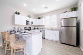 Tolleson apartment for rent - A modern kitchen with a center island and stainless steel appliances. at Vistoria At Country Place Apartments, Tolleson, 85353