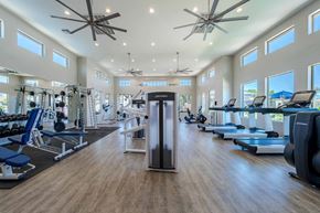 Surprise apartment for rent - A spacious gym with a variety of equipment and a ceiling fan at Vistoria At Marley Park Apartments, Surprise, 85379