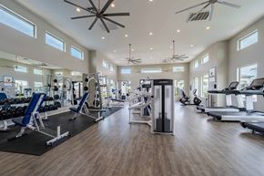 Peoria apartment for rent - A spacious gym with a variety of equipment and a ceiling fan.